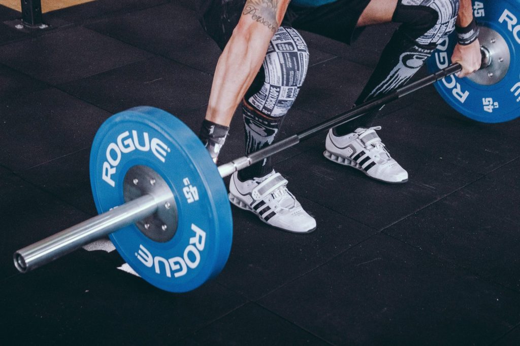A focused male athlete lifting weights in a gym setting.