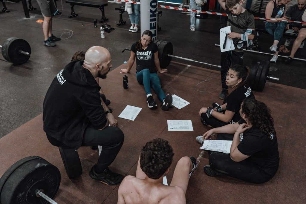 a group of people sitting on the ground in a gym